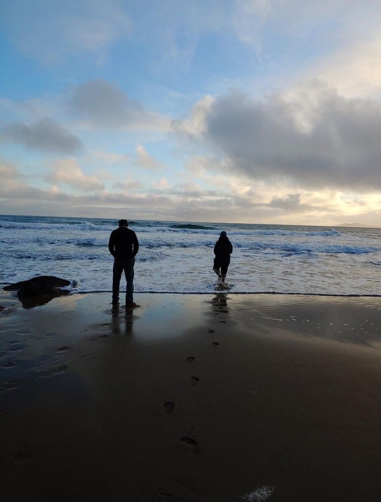 Two people standing along the shoreline of the Dingle Peninsula in Ireland 