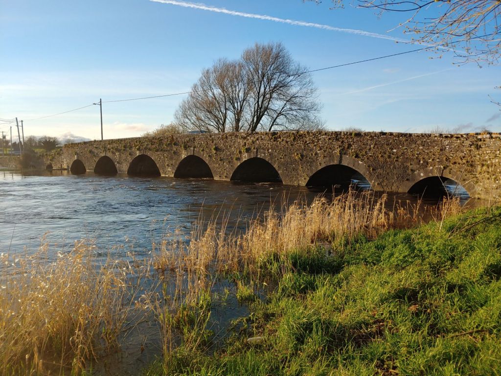 Stone arch bridge crossing a river with grassy banks