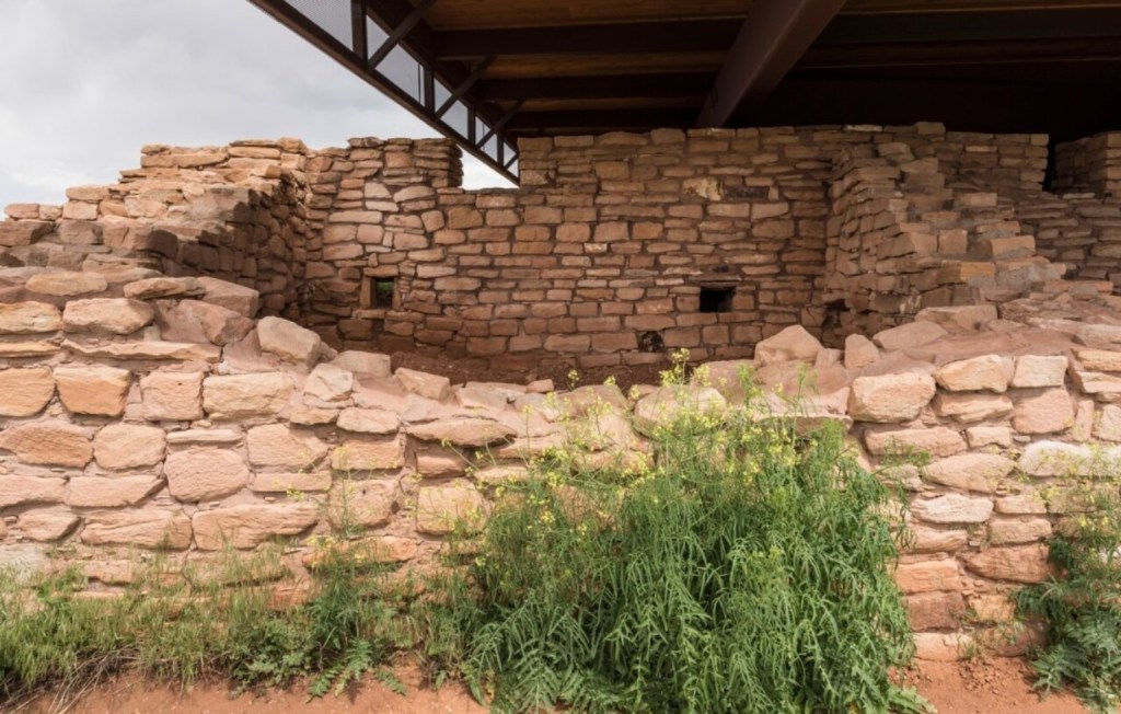 Ancient stone masonry walls of Lowry Pueblo sheltered by a protective roof in Canyons of the Ancients National Monument, Colorado