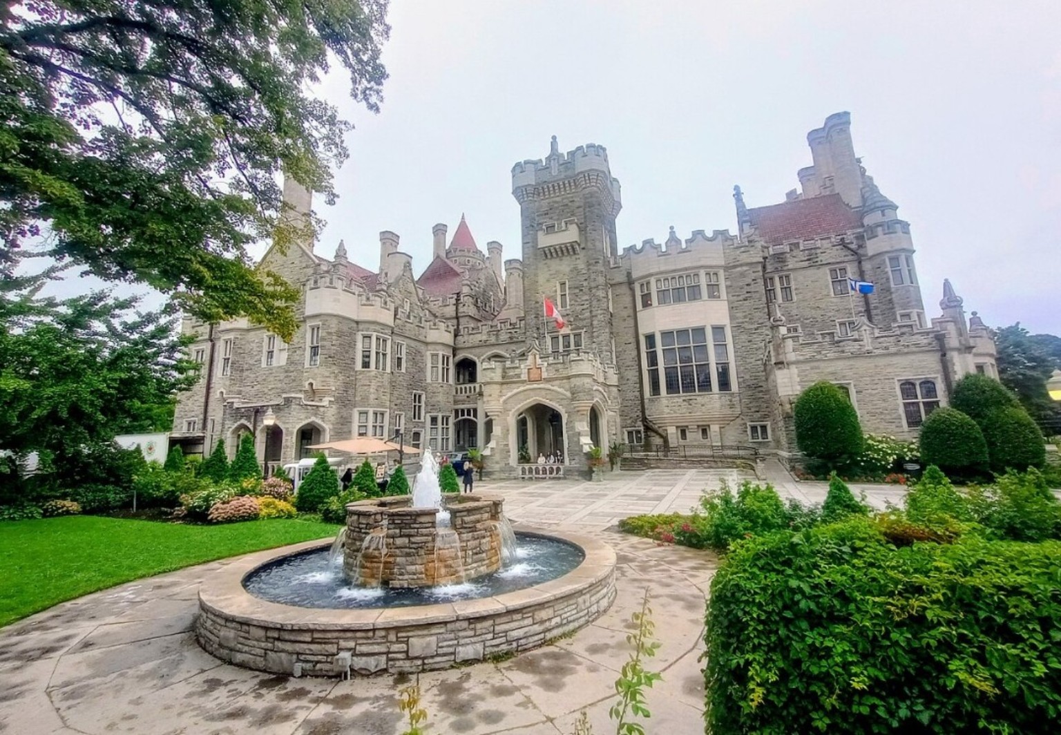 Casa Loma castle in Toronto with stone towers, a landscaped courtyard, and a circular fountain in front.