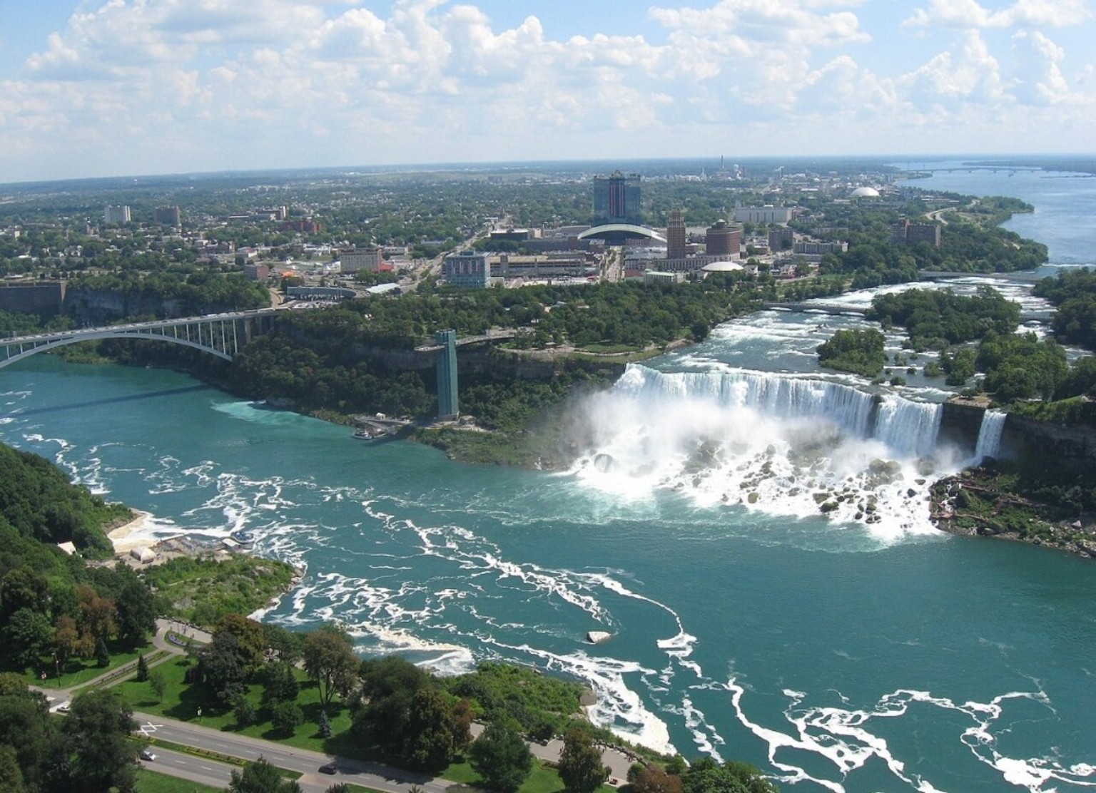 Elevated view of the American Falls and Bridal Veil Falls, turquoise Niagara River, Rainbow Bridge, and Niagara Falls New York.