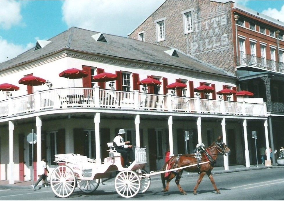 A horse-drawn carriage outside a balcony-lined building in New Orleans' French Quarter.
